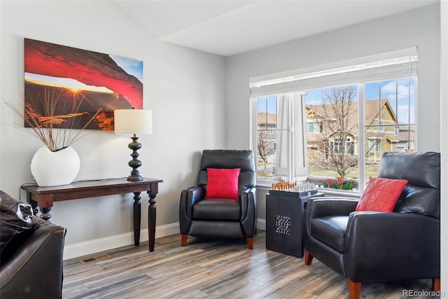 living area featuring visible vents, baseboards, and wood finished floors