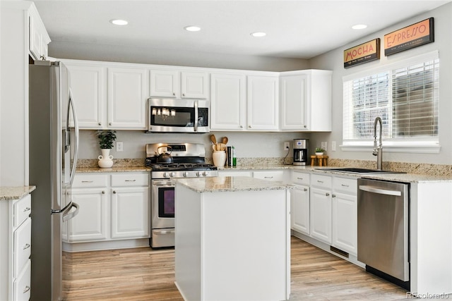 kitchen with a sink, appliances with stainless steel finishes, light wood-style flooring, and white cabinets