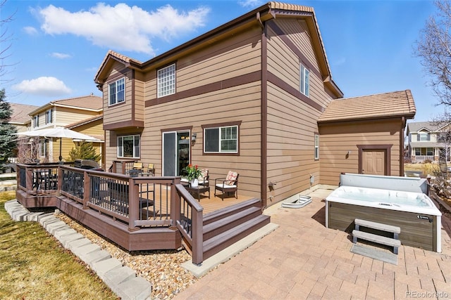 rear view of property featuring a deck and a hot tub