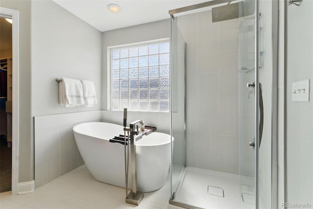 bathroom featuring tile walls, a stall shower, and a freestanding bath