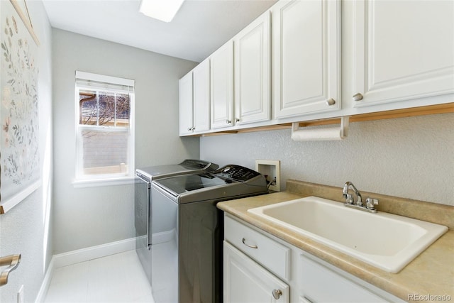 laundry area with a sink, cabinet space, baseboards, and separate washer and dryer