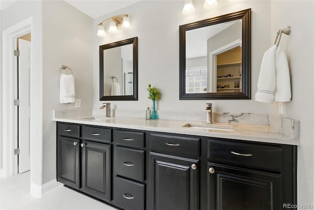 full bath featuring double vanity, tile patterned flooring, and a sink