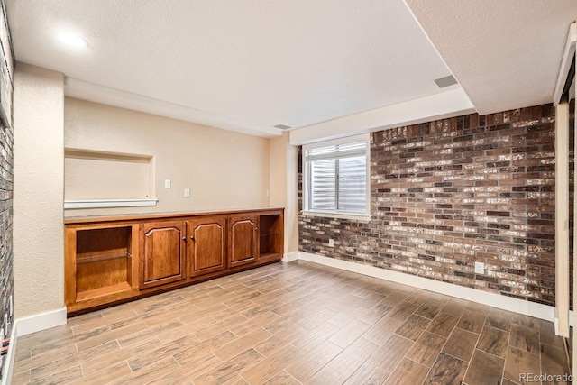 spare room with a textured ceiling and brick wall