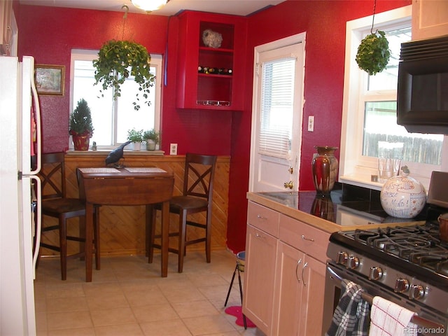 5618 Carr St, Arvada, CO 80002 - kitchen with gas stove, freestanding refrigerator, black microwave, light tile patterned flooring, and plenty of natural light