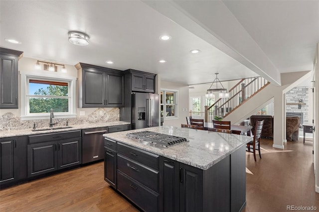 kitchen with sink, a center island, pendant lighting, appliances with stainless steel finishes, and light wood-type flooring