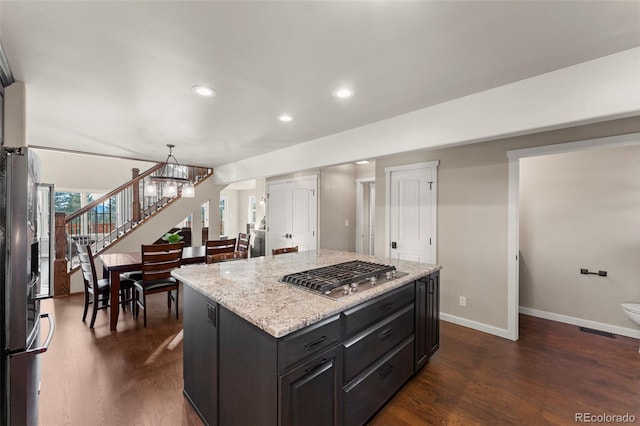 kitchen featuring a center island, dark hardwood / wood-style floors, a notable chandelier, pendant lighting, and stainless steel gas stovetop