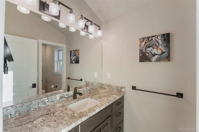 bathroom with toilet, vanity, and vaulted ceiling