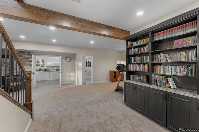 sitting room featuring beamed ceiling and light carpet