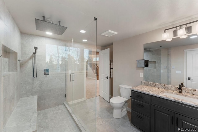 bathroom featuring tile patterned floors, vanity, a shower with shower door, and toilet