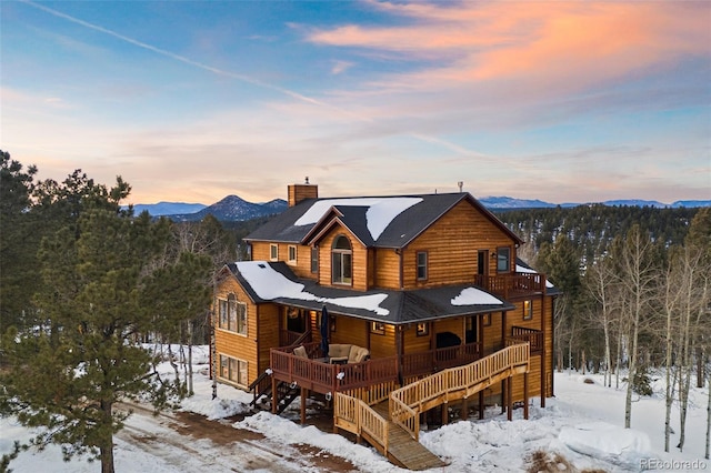 snow covered back of property featuring a mountain view