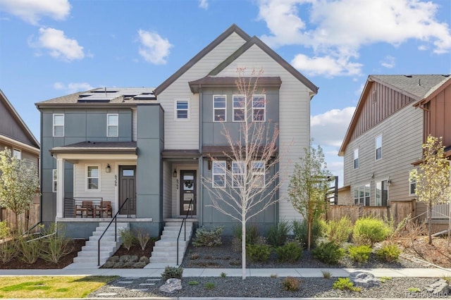craftsman-style home featuring covered porch, fence, and roof mounted solar panels