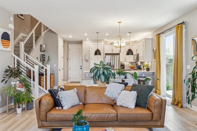 living room with light wood-style flooring, recessed lighting, stairway, a notable chandelier, and baseboards