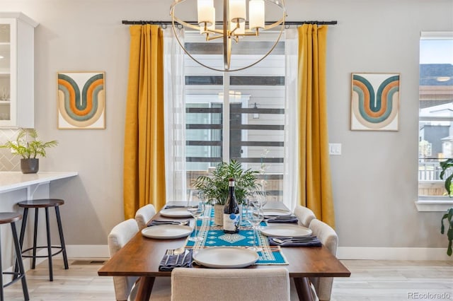 dining room featuring light wood-type flooring, baseboards, and a notable chandelier