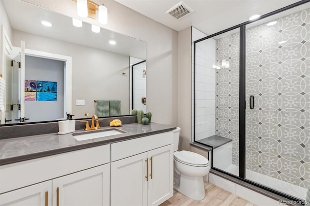 bathroom featuring vanity, a stall shower, toilet, visible vents, and wood finished floors