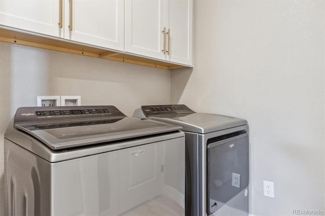 clothes washing area with washing machine and dryer and cabinet space