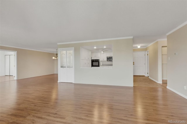 unfurnished living room with ornamental molding, light wood-type flooring, a chandelier, and baseboards