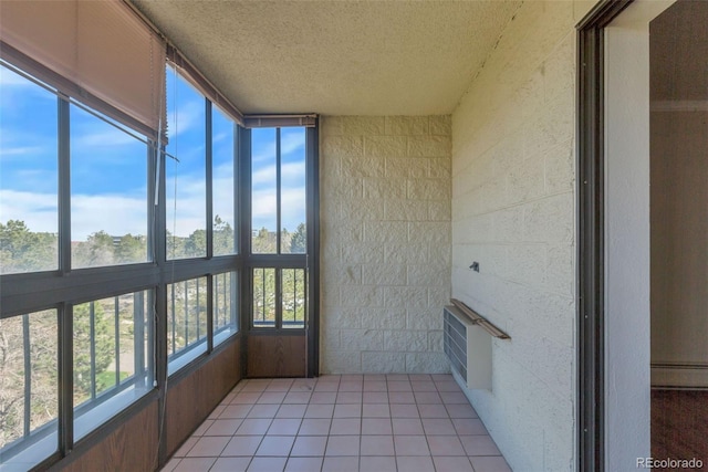 unfurnished sunroom featuring a textured ceiling, plenty of natural light, and tile patterned flooring