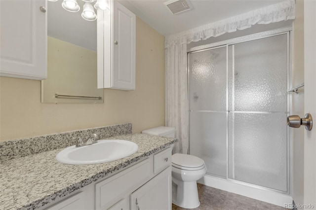 bathroom with a shower stall, toilet, vanity, and tile patterned floors
