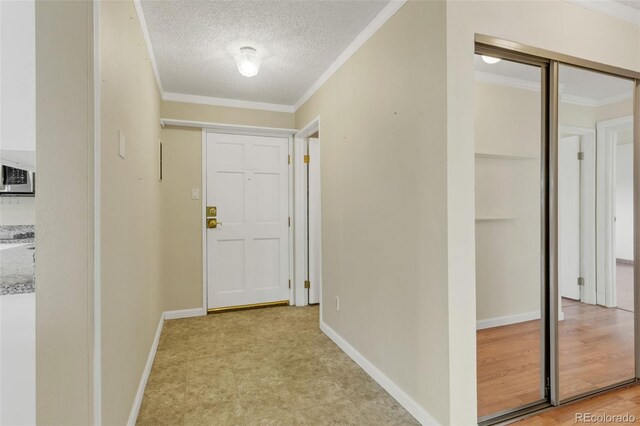 corridor featuring crown molding, a textured ceiling, and baseboards