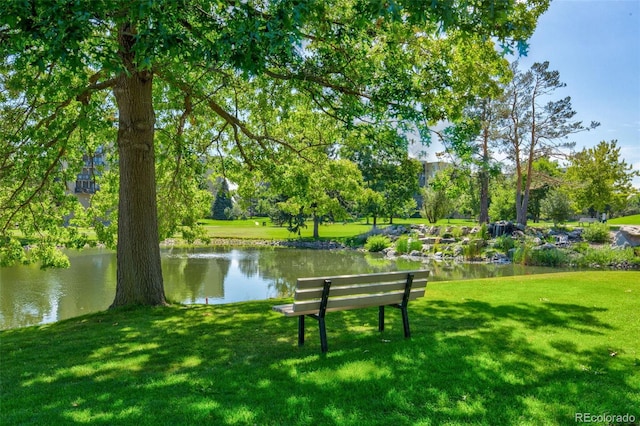 surrounding community with a water view and a lawn