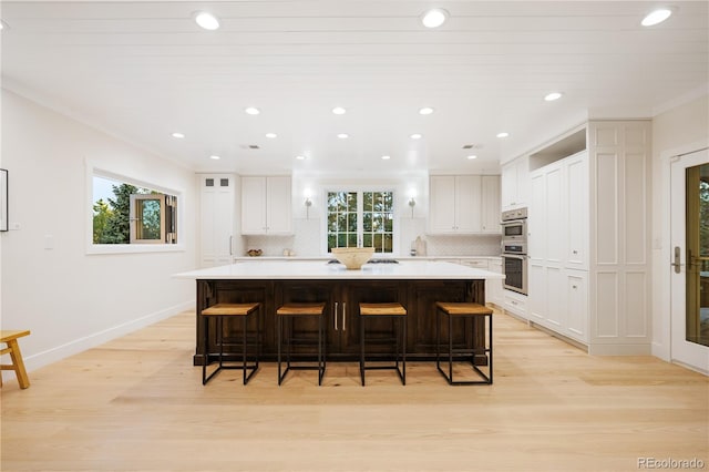 kitchen featuring white cabinets, light wood-style flooring, and tasteful backsplash