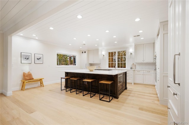 kitchen featuring backsplash, light wood-type flooring, a breakfast bar area, and recessed lighting