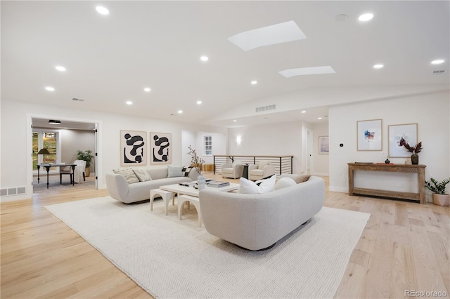 living area with vaulted ceiling with skylight, light wood-type flooring, visible vents, and recessed lighting