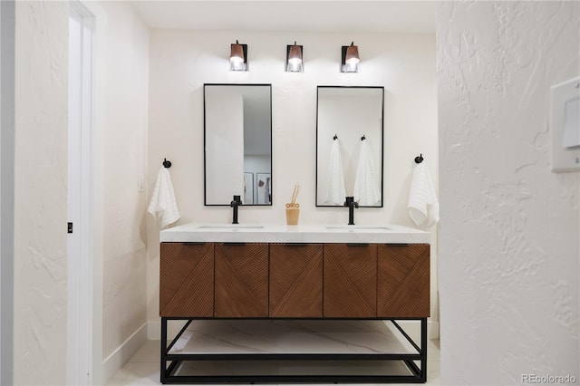 bathroom featuring double vanity, a textured wall, and a sink