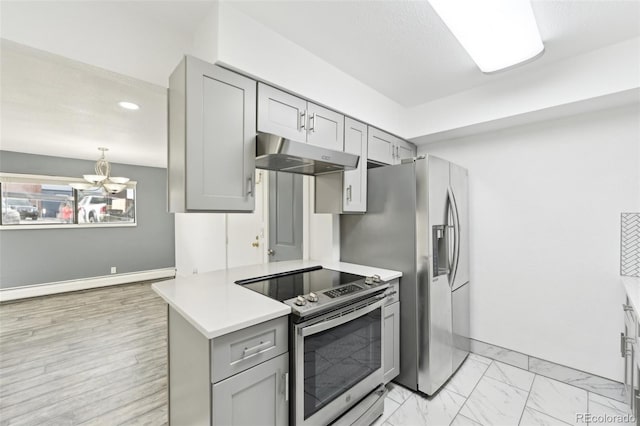 kitchen with gray cabinetry, kitchen peninsula, an inviting chandelier, and appliances with stainless steel finishes