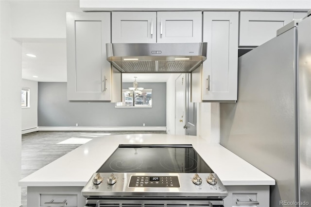 kitchen featuring stainless steel appliances, plenty of natural light, exhaust hood, and a notable chandelier