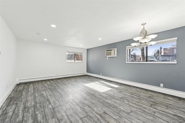 unfurnished room with wood-type flooring, an AC wall unit, an inviting chandelier, and baseboard heating