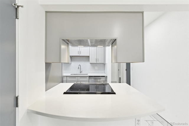 kitchen featuring tasteful backsplash, sink, dishwashing machine, kitchen peninsula, and black electric cooktop