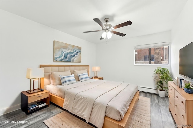 bedroom featuring a baseboard heating unit, hardwood / wood-style floors, and ceiling fan