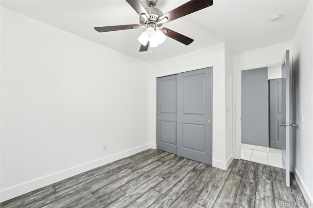 unfurnished bedroom featuring dark hardwood / wood-style flooring, a closet, and ceiling fan