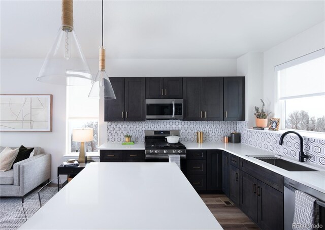 11914 W 57th Dr, Arvada, CO 80002 - kitchen featuring stainless steel appliances, a sink, light countertops, backsplash, and dark cabinetry