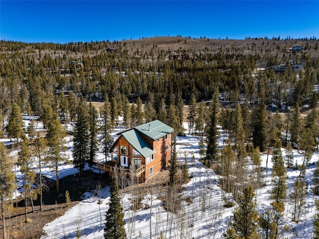 snowy aerial view featuring a wooded view