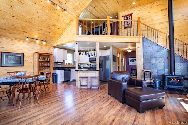 living room featuring a wood stove, wooden ceiling, wooden walls, and dark wood-style flooring