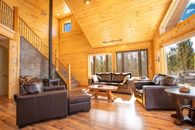 living area with wood finished floors, wood ceiling, wood walls, and stairs