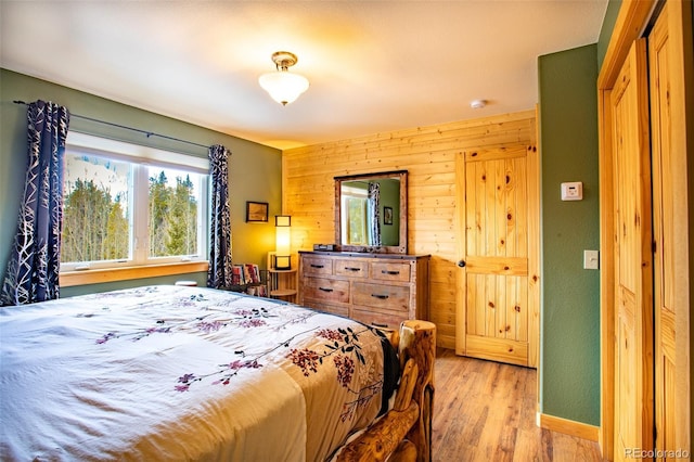 bedroom with wooden walls and light wood-style floors