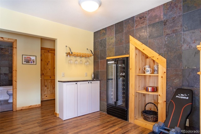 kitchen with wine cooler, tile walls, dark countertops, white cabinets, and wood finished floors