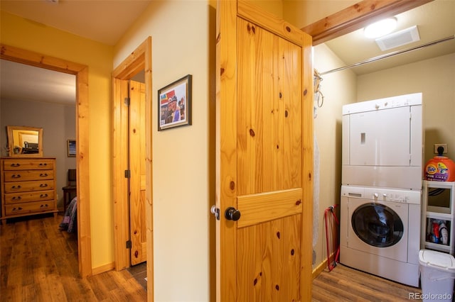 washroom with laundry area, visible vents, stacked washer / dryer, and wood finished floors