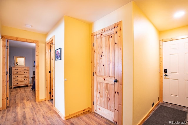 corridor with light wood-style floors and baseboards