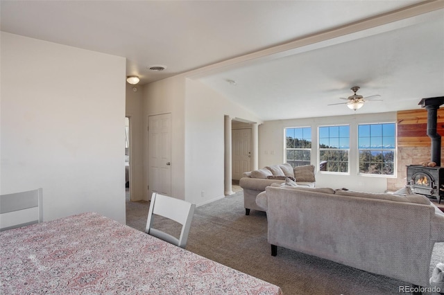 interior space featuring a wood stove, carpet, visible vents, and a ceiling fan