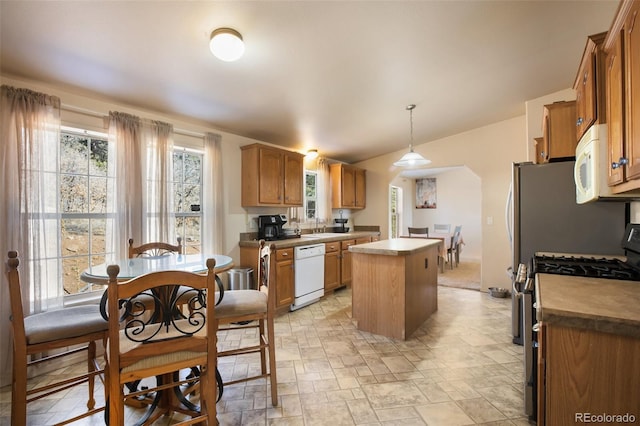 kitchen with brown cabinetry, a center island, white appliances, and pendant lighting