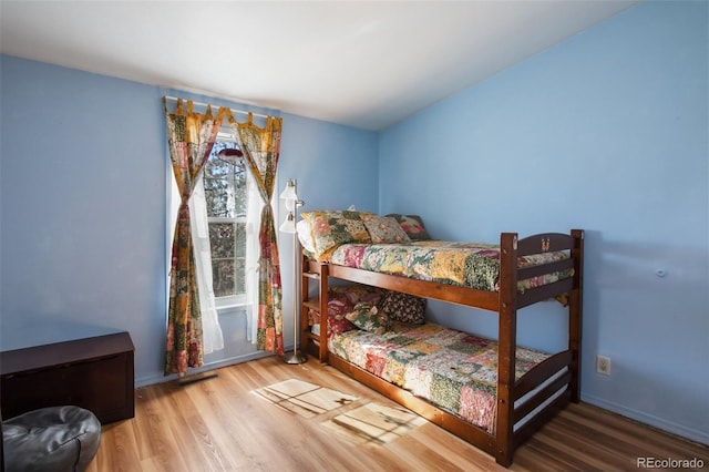 bedroom with wood finished floors, visible vents, and baseboards