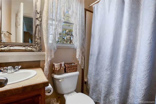 bathroom with curtained shower, vanity, and toilet