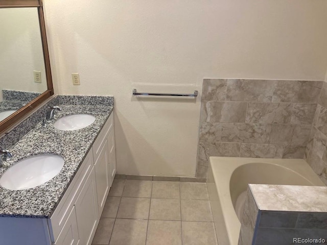 bathroom featuring tile patterned flooring, vanity, and tiled tub