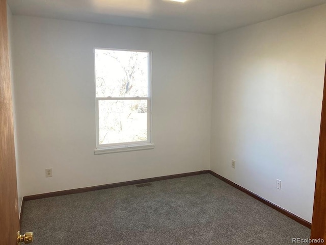 unfurnished room with dark colored carpet and a wealth of natural light