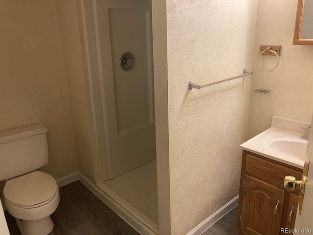 bathroom with walk in shower, hardwood / wood-style flooring, vanity, and toilet