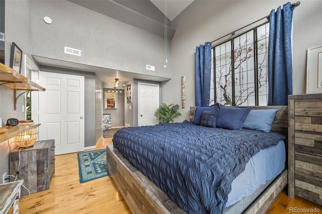 bedroom featuring wood-type flooring and high vaulted ceiling